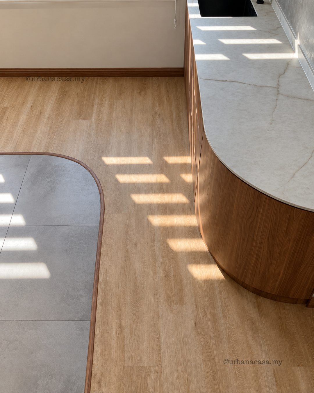 Curved transition between wood-look flooring and stone-look tiles
